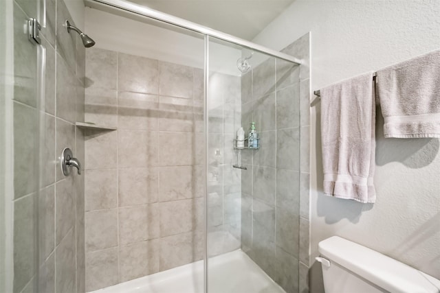 full bathroom with toilet, a textured wall, and a shower stall