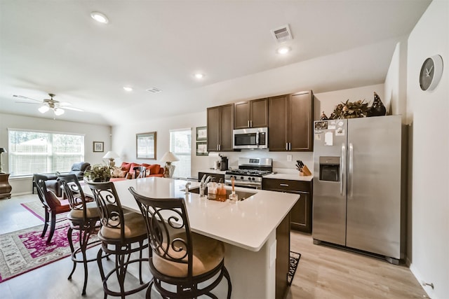 kitchen with dark brown cabinetry, light countertops, stainless steel appliances, open floor plan, and visible vents