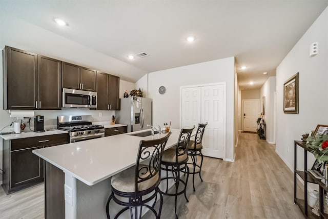 kitchen with an island with sink, stainless steel appliances, light wood-type flooring, and visible vents