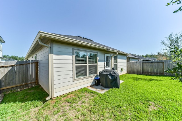 rear view of property featuring a yard and a fenced backyard