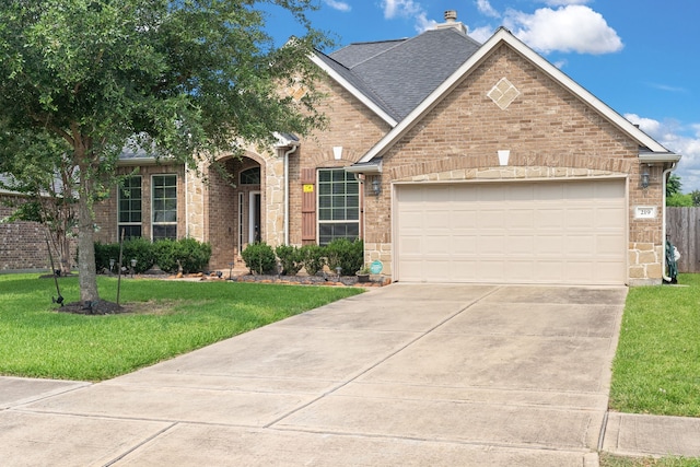 traditional-style house featuring a garage, a front yard, driveway, and brick siding