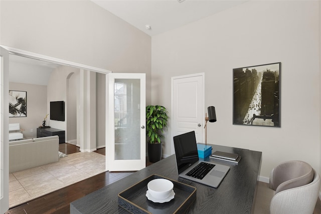 office area featuring baseboards, wood finished floors, and high vaulted ceiling