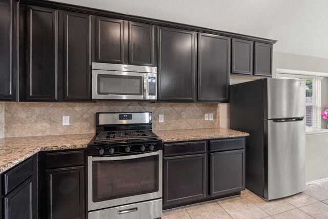 kitchen featuring light tile patterned floors, appliances with stainless steel finishes, tasteful backsplash, and light stone countertops
