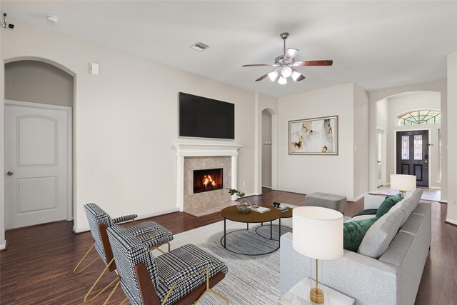 living area featuring arched walkways, ceiling fan, visible vents, and dark wood-type flooring