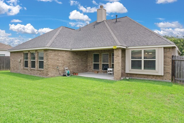 rear view of house with fence, a chimney, a patio area, and roof with shingles