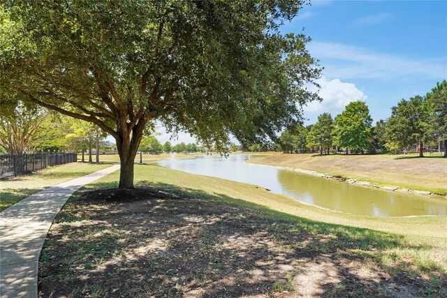 view of property's community with a water view, fence, and a yard