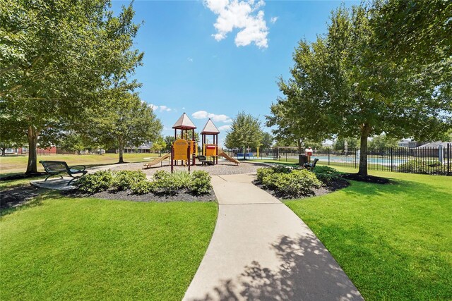 community play area featuring a lawn and fence