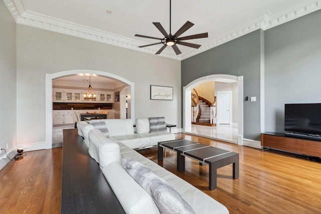 7711 Oxfordshire Dr, Spring, TX 77379 - living area with arched walkways, ornamental molding, ceiling fan with notable chandelier, and wood finished floors