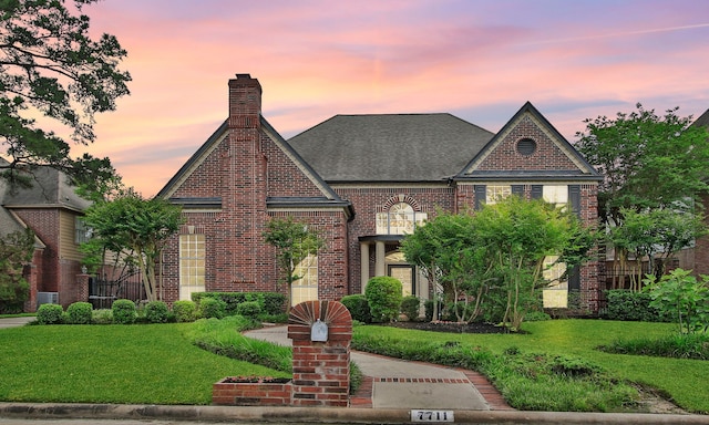 7711 Oxfordshire Dr, Spring, TX 77379 - view of front facade featuring a chimney, a lawn, brick siding, central AC, and a shingled roof