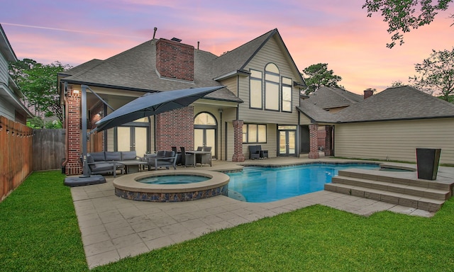 7711 Oxfordshire Dr, Spring, TX 77379 - back of property at dusk featuring brick siding, an outdoor living space, french doors, and a patio
