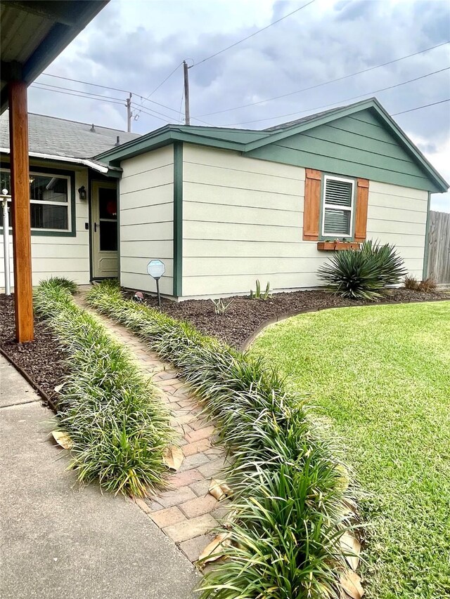 view of property exterior with a lawn and fence