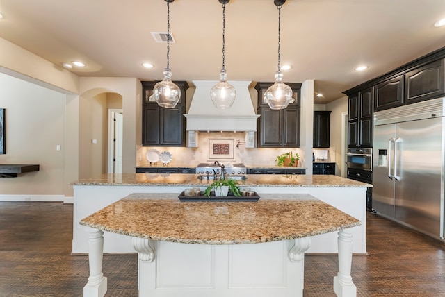 kitchen featuring a spacious island, a kitchen bar, custom range hood, dark wood finished floors, and stainless steel appliances