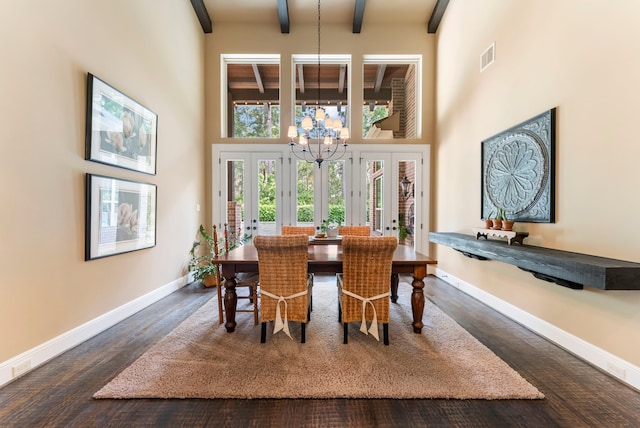dining space with a towering ceiling, wood finished floors, a chandelier, and beamed ceiling