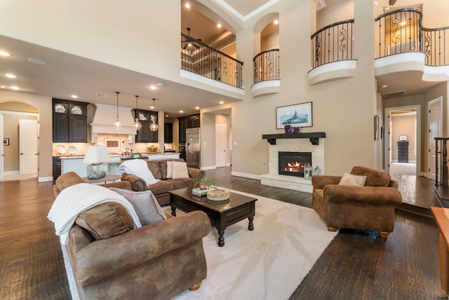 living area featuring dark wood-style flooring, arched walkways, baseboards, and a fireplace
