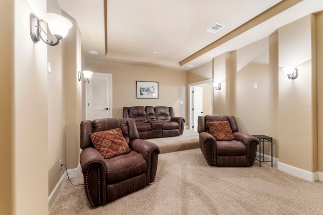 carpeted living room with baseboards, a raised ceiling, and visible vents