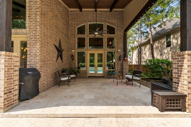 entrance to property featuring fence, brick siding, a patio area, french doors, and a ceiling fan