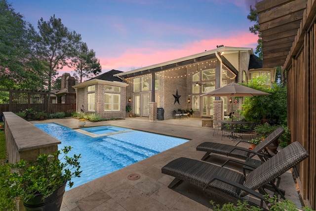 view of pool with a patio area, fence, and a pool with connected hot tub