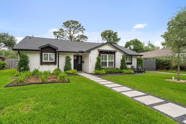 single story home featuring fence, a shingled roof, and a front lawn