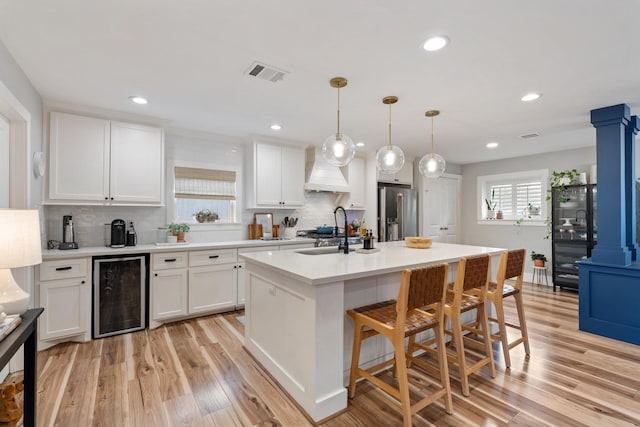 kitchen with visible vents, wine cooler, high quality fridge, white cabinetry, and a sink