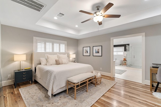 bedroom with visible vents, recessed lighting, light wood finished floors, and a tray ceiling