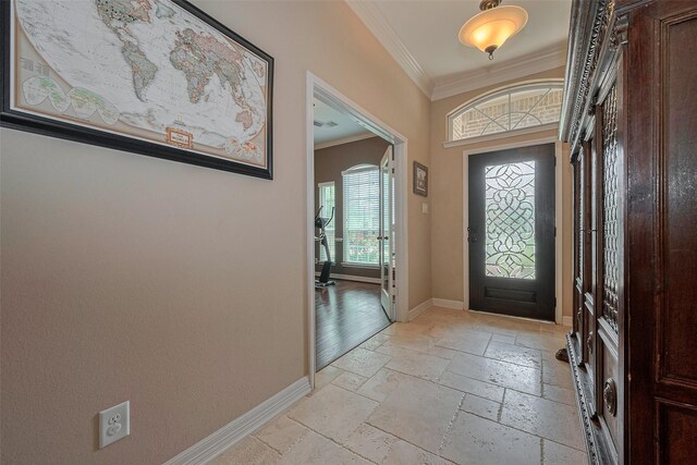 entryway featuring baseboards, ornamental molding, and stone tile floors