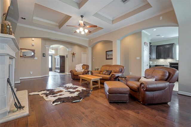 living area featuring arched walkways, a ceiling fan, ornamental molding, and dark wood-type flooring