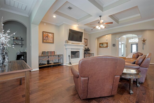 living room with crown molding, a fireplace with raised hearth, ceiling fan, and wood finished floors