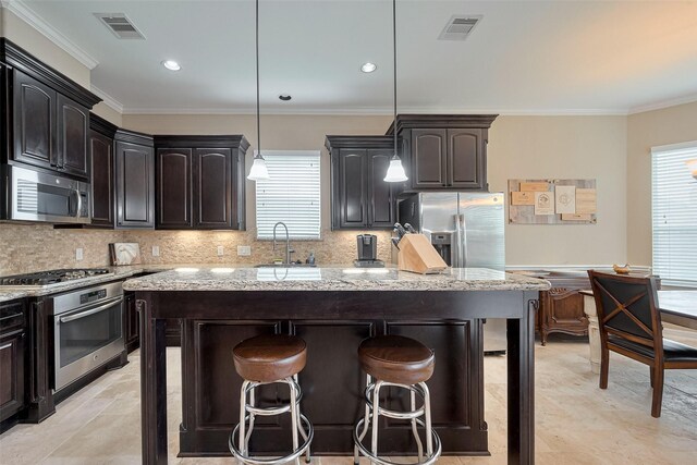 kitchen with appliances with stainless steel finishes, a center island, a breakfast bar area, and visible vents