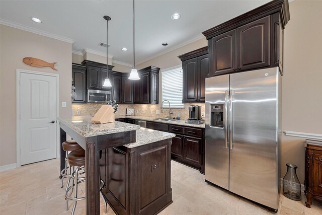 kitchen featuring light stone counters, a sink, a center island, stainless steel appliances, and backsplash