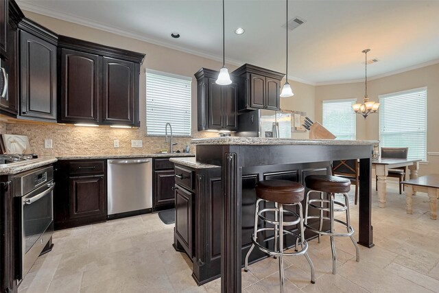 kitchen with a sink, stainless steel appliances, tasteful backsplash, a kitchen island, and a kitchen bar