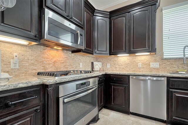 kitchen with stainless steel appliances, light stone countertops, a sink, and tasteful backsplash