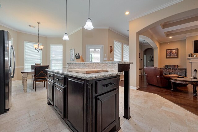 kitchen with crown molding, freestanding refrigerator, visible vents, open floor plan, and dark cabinetry
