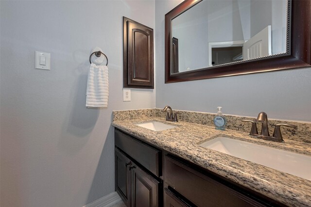 bathroom with double vanity, a sink, and baseboards