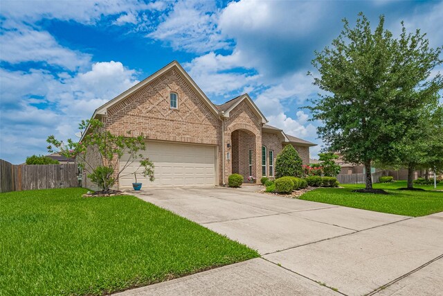 traditional home featuring a front lawn, fence, brick siding, concrete driveway, and an attached garage