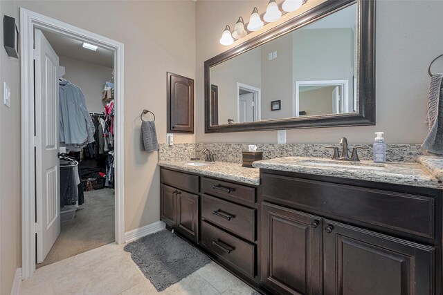bathroom with double vanity, a sink, baseboards, and a walk in closet