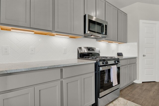 18331 Yaupon Bough Ln, Tomball, TX 77377 - kitchen featuring light stone countertops, appliances with stainless steel finishes, gray cabinets, and tasteful backsplash