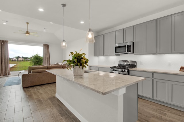 18331 Yaupon Bough Ln, Tomball, TX 77377 - kitchen featuring ceiling fan, appliances with stainless steel finishes, open floor plan, wood finished floors, and gray cabinetry