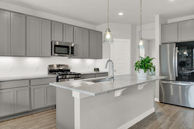18331 Yaupon Bough Ln, Tomball, TX 77377 - kitchen with stainless steel appliances, gray cabinetry, a sink, and light wood-style flooring