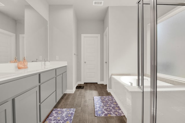 18331 Yaupon Bough Ln, Tomball, TX 77377 - bathroom with double vanity, a garden tub, visible vents, wood finished floors, and baseboards