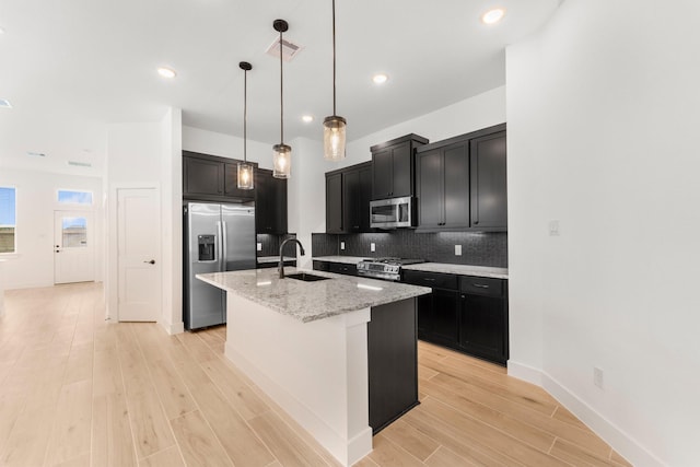 21517 Witham Promenade Ln, Magnolia, TX 77355 - kitchen with appliances with stainless steel finishes, a sink, tasteful backsplash, dark cabinets, and recessed lighting