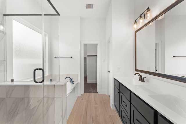 21517 Witham Promenade Ln, Magnolia, TX 77355 - full bath with a bath, a stall shower, a walk in closet, double vanity, and wood finished floors