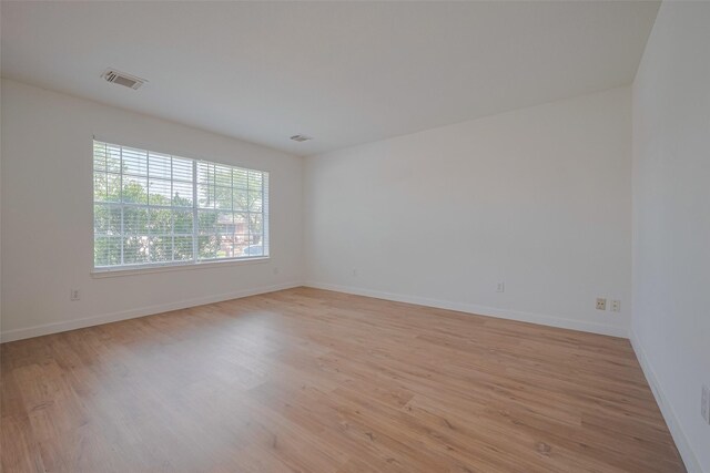 spare room featuring baseboards, light wood-type flooring, and visible vents