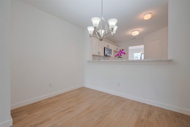 unfurnished dining area featuring baseboards, an inviting chandelier, and light wood-type flooring