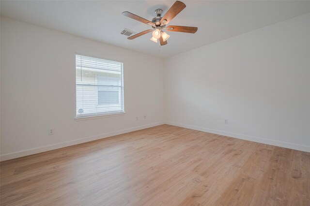 empty room with light wood-style floors, baseboards, ceiling fan, and visible vents
