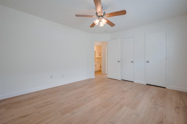 unfurnished bedroom featuring light wood-style floors, a ceiling fan, baseboards, and two closets