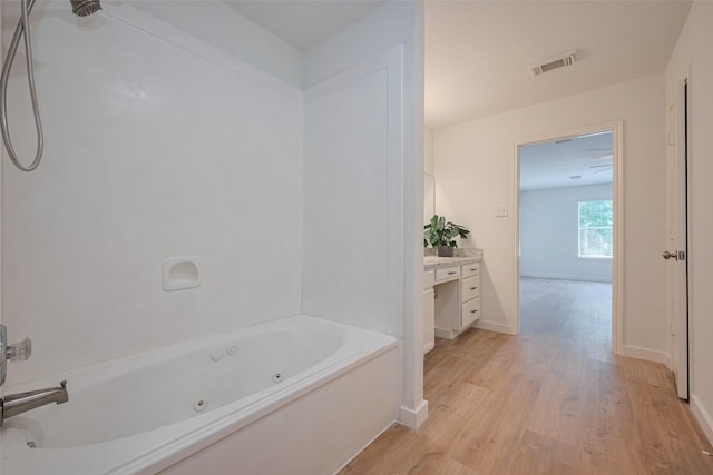 bathroom with vanity, a whirlpool tub, baseboards, wood finished floors, and visible vents