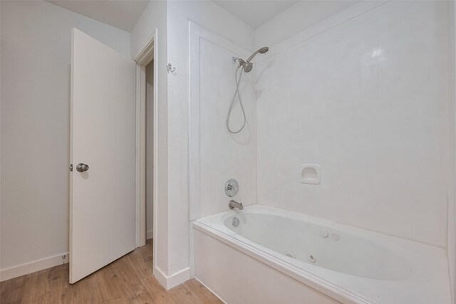 bathroom with baseboards, wood finished floors, and shower / washtub combination