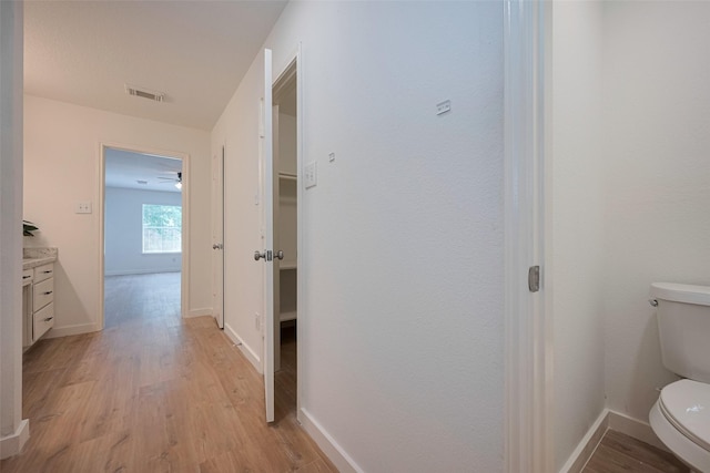 hallway with visible vents, light wood finished floors, and baseboards