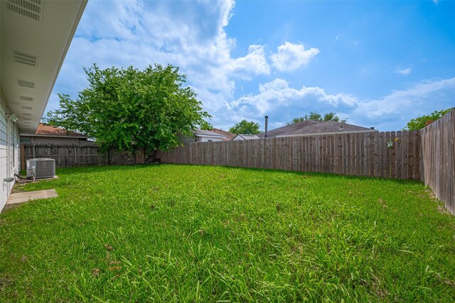 view of yard with a fenced backyard and central AC unit