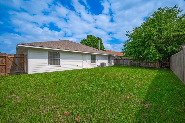 rear view of property with a lawn, a fenced backyard, and cooling unit